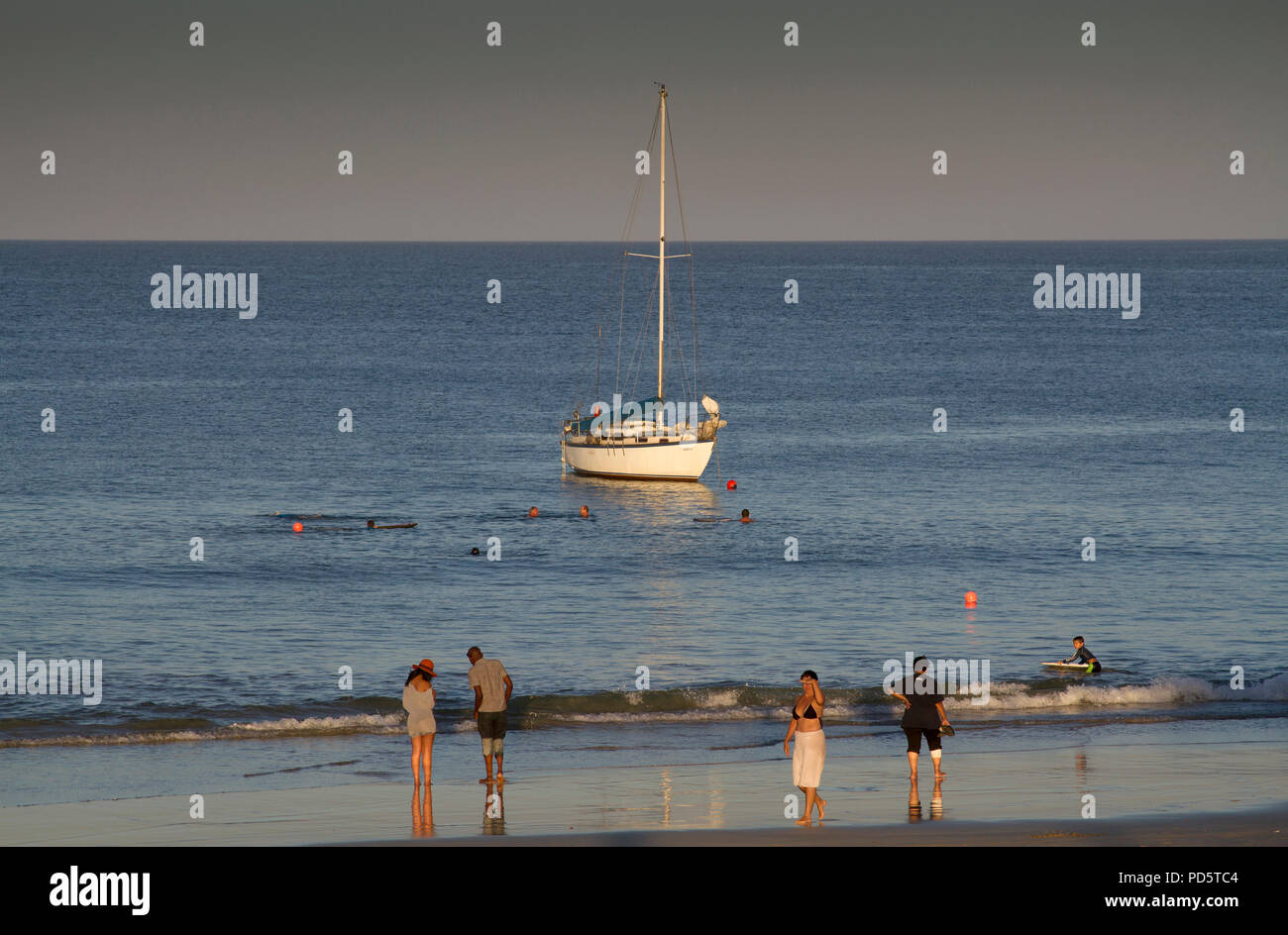 Touristen am Strand mit Yacht in See Stockfoto