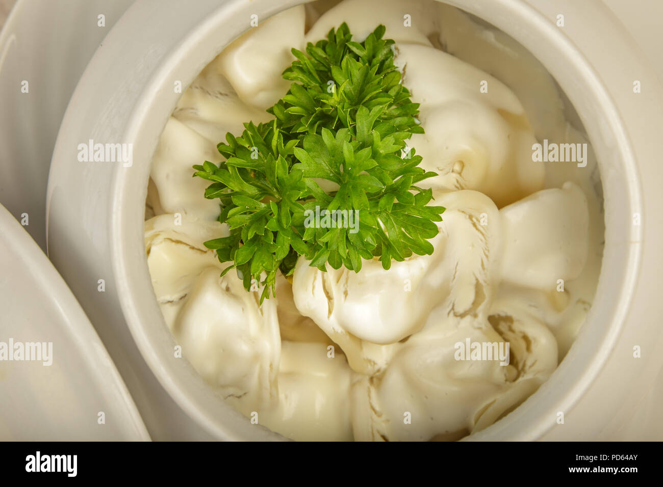 Knödel in einem weißen Topf mit Sauerrahm und grünen auf einer hölzernen Hintergrund. Stockfoto