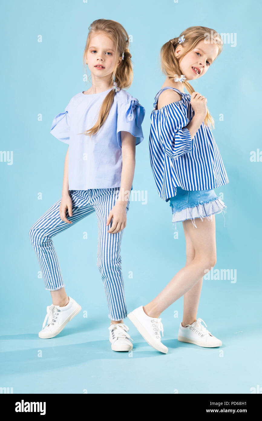 Mädchen Zwillinge in Hellblau Kleidung Stellen auf einem blauen Hintergrund  Stockfotografie - Alamy