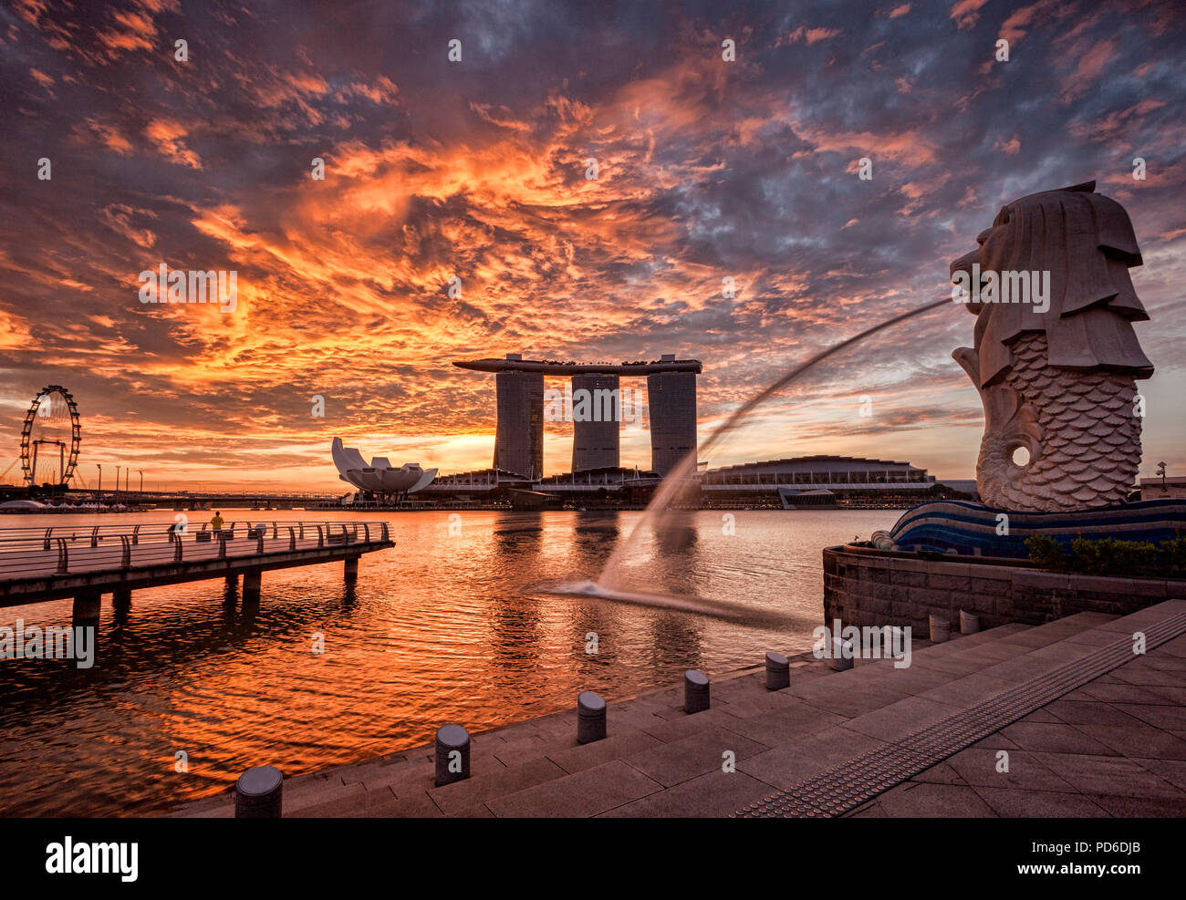 Skyline von Singapur bei Sonnenaufgang, mit der Merlion, das Marina Bay Sands, der Kunst und Wissenschaft Museum und der Singapore Flyer, alle unter einem dramatischen Sunrise Stockfoto