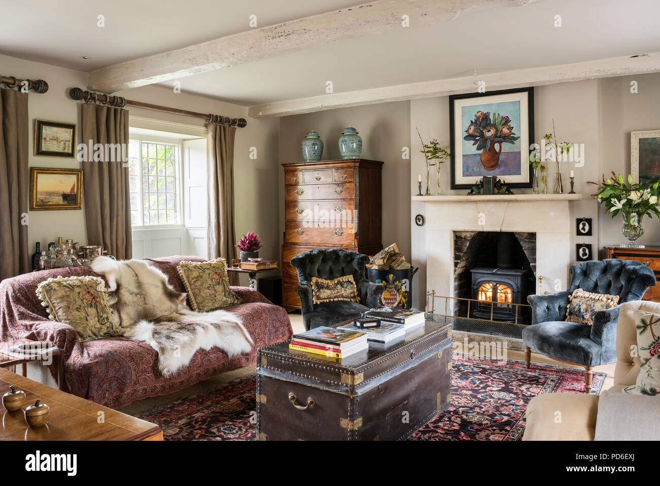 Stühle am lit Fireside mit tierischen Haut auf Sofa und Schwarz reisen Brust Geknöpft Stockfoto