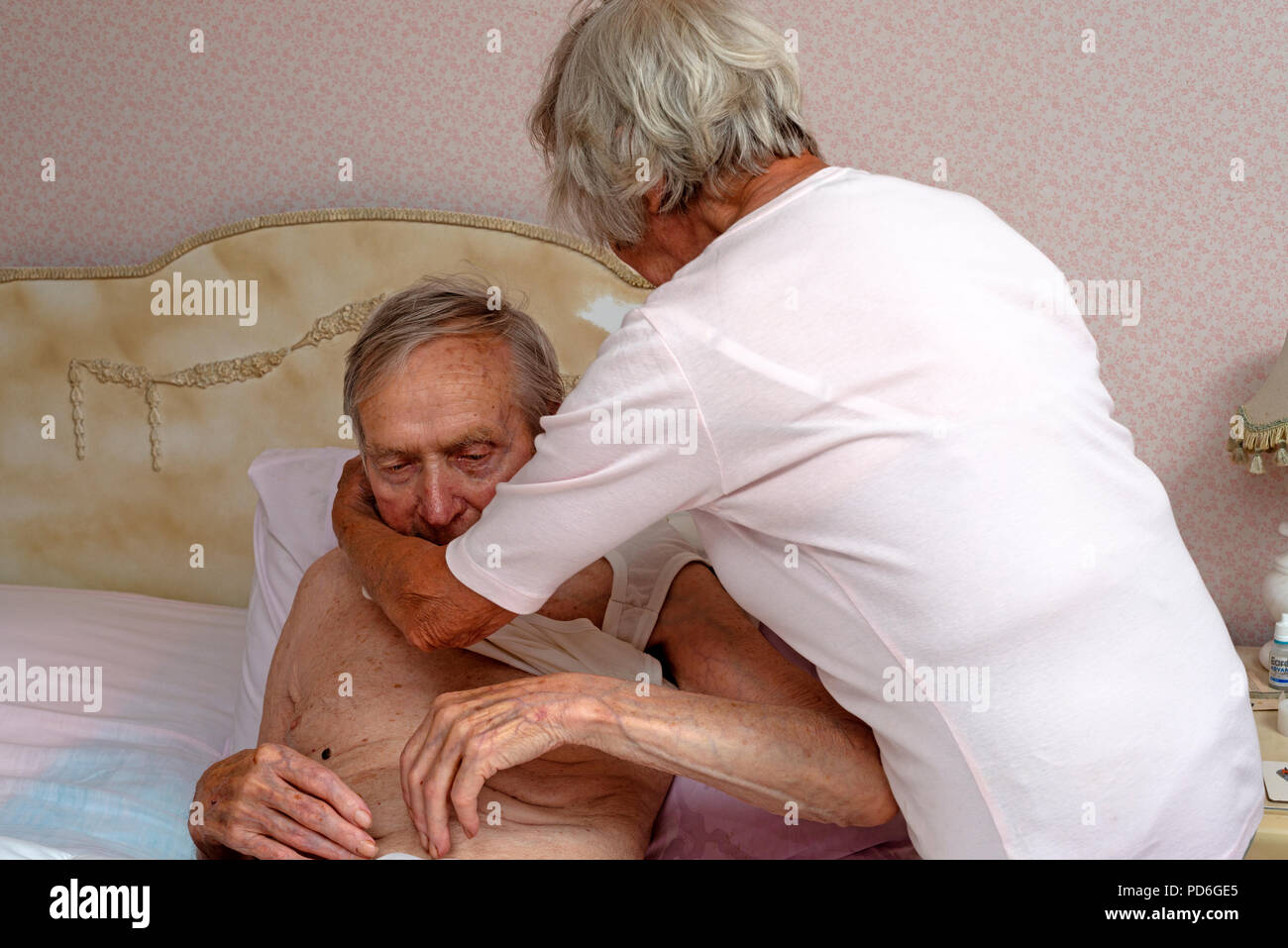 Ältere Menschen geholfen wird von seiner Schwester zum Umziehen Stockfoto