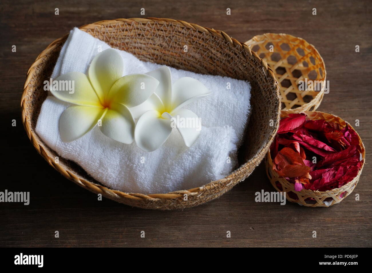 Weiße Blume dekorieren auf dem Handtuch, die auf Warenkorb und trocken Rose auf Holztisch, spa-Konzept. Stockfoto