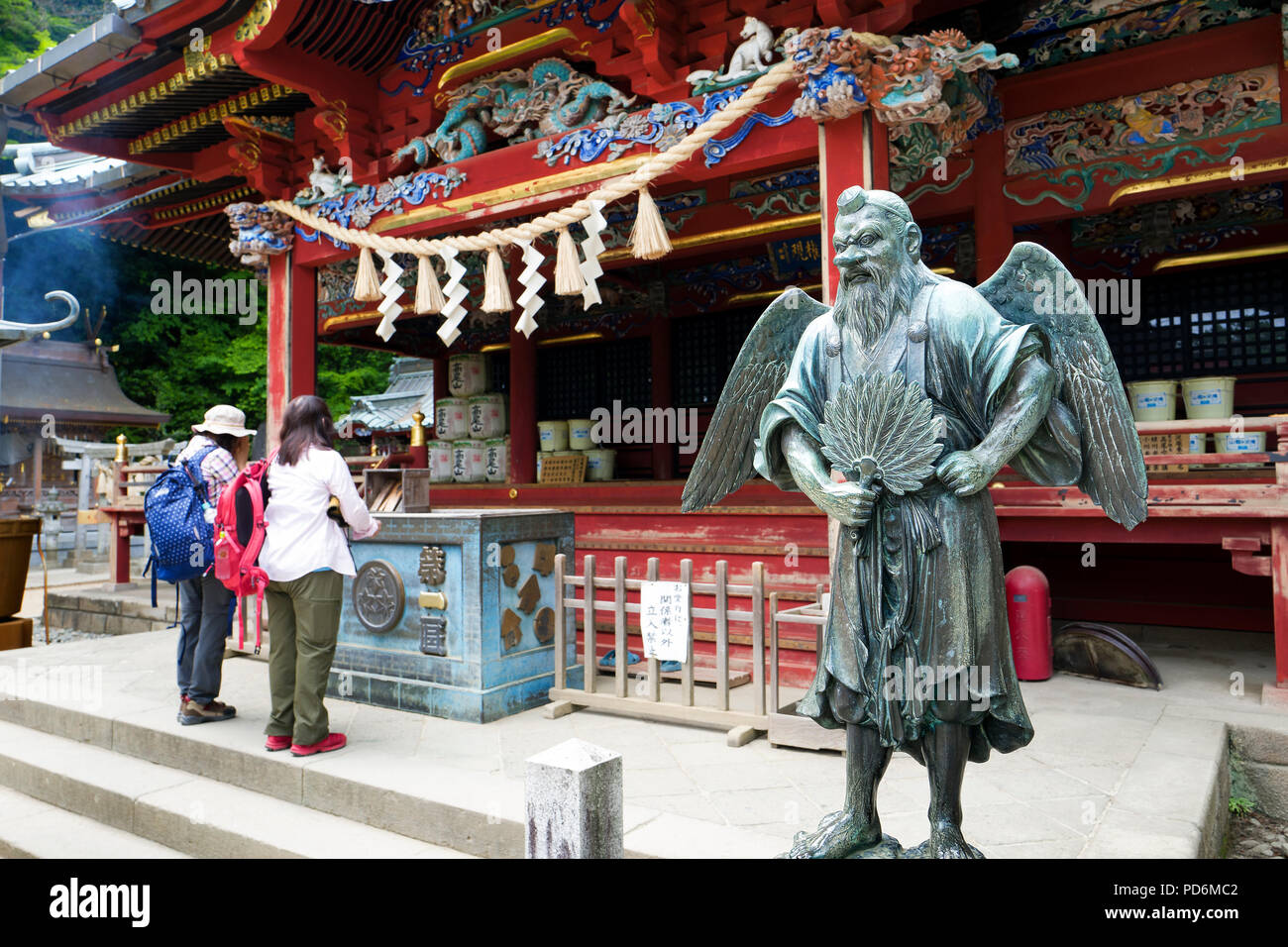 Japan, Insel Honshu, Kanto, Takao, Menschen beten und eine Statue eines tengu Gott. Stockfoto