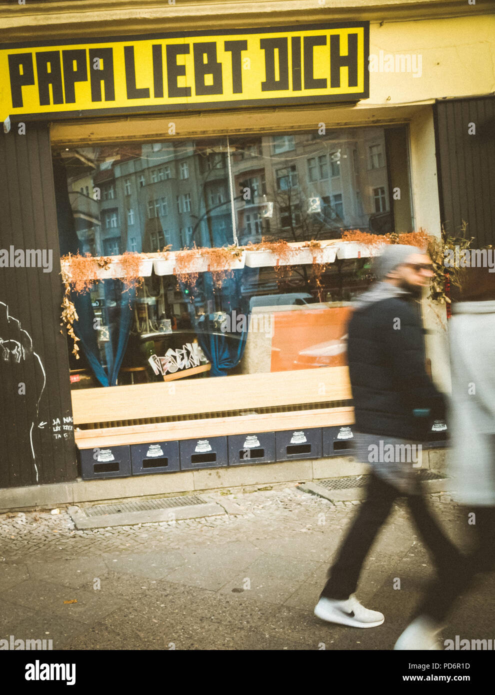 Verschwommener Fußgänger passiert die Schaufensteranzeige mit der Aufschrift "Papa liebt dich", Bewegungsunschärfe, Neukölln, Berliner Straßenleben Stockfoto