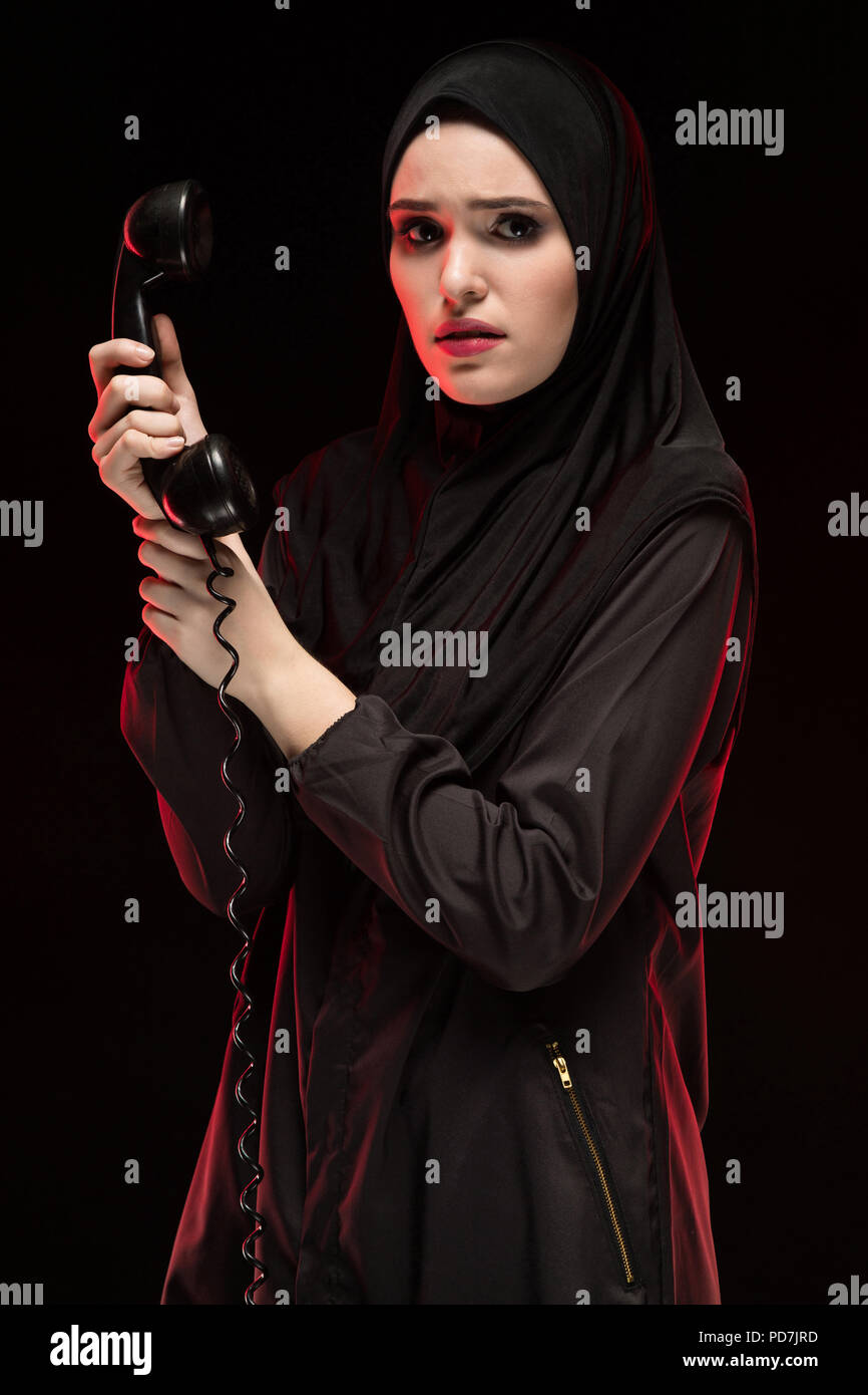 Porträt der schönen schweren Angst junge muslimische Frau mit schwarzen Hijab um Hilfe ruft auf schwarzem Hintergrund Stockfoto