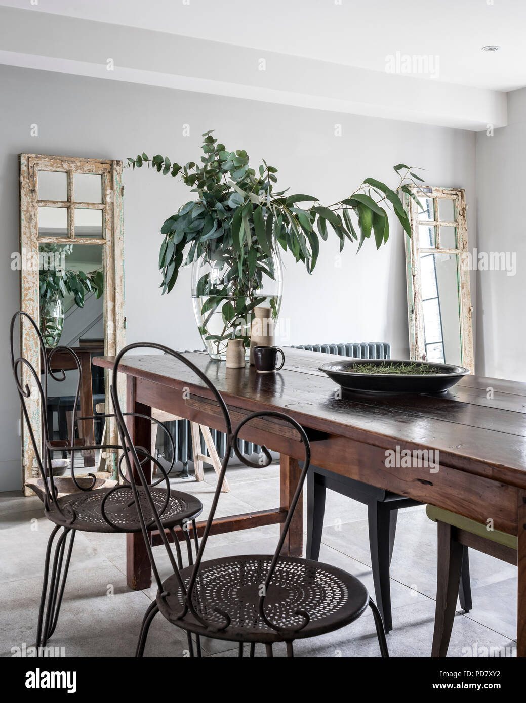 Vintage Metall Stühle und ein paar von Phillipe Hurel Hocker Holztisch in schicke Küche mit Holzofen Stockfoto