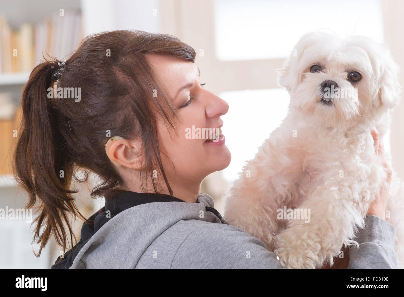 Junge, lächelnde Frau tragen Deaf Aid und ihrem kleinen Hund Holding Stockfoto