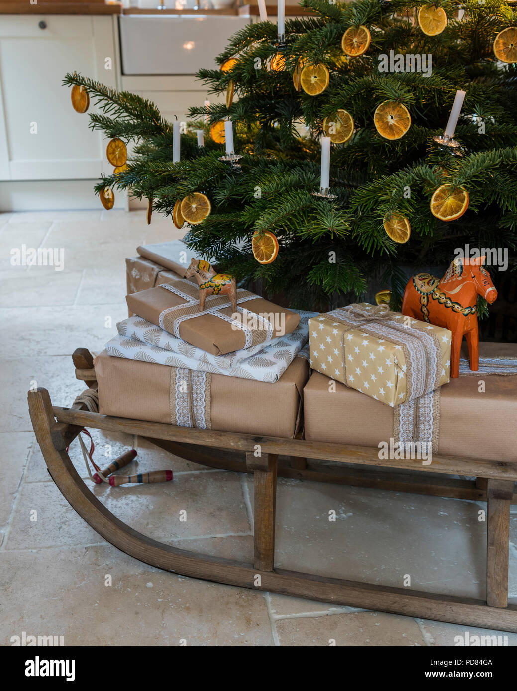 Eingepackten Geschenke auf einem hölzernen Schlitten unter Kerzenlicht beleuchteten Weihnachtsbaum Stockfoto