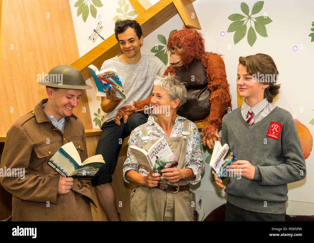 Edinburgh Fringe Festival, Edinburgh, Großbritannien. 7. August 2018. Central Library, Edinburgh, Schottland, Vereinigtes Königreich: Fotoshooting für Cast von Fringe zeigt auf der Grundlage der KINDERBÜCHER von Michael Morpurgo. Scamp Theater Private friedlich mit Andy Daniel, Poonamallee Produktion ein Elefant im Garten mit Lizzie gespielt von Alison Reid; Aquila der Krieg von Jenkin's Ohr mit Toby Jenkins gespielt von Atticus Christie-Miller und WildChild Produktion Kensuke's Königreich mit Michael, gespielt von Aaron Douglas; Kinder- Bibliothek mit Schauspielern Bücher lesen Stockfoto