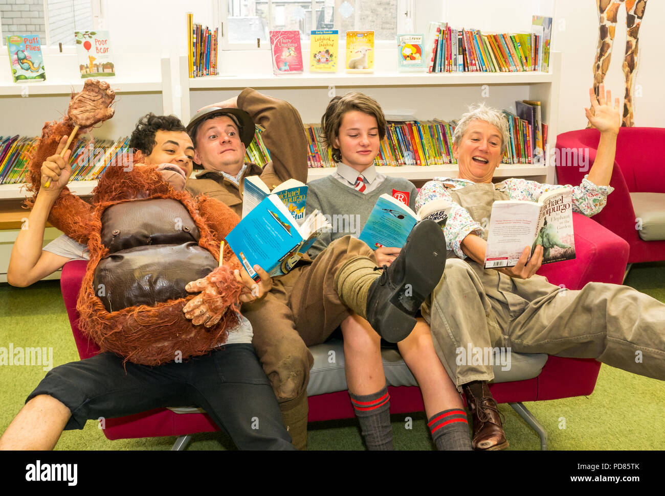 Edinburgh Fringe Festival, Edinburgh, Großbritannien. 7. August 2018. Central Library, Edinburgh, Schottland, Vereinigtes Königreich: Fotoshooting für Cast von Fringe zeigt auf der Grundlage der KINDERBÜCHER von Michael Morpurgo. Scamp Theater Private friedlich mit Andy Daniel, Poonamallee Produktion ein Elefant im Garten mit Lizzie gespielt von Alison Reid; Aquila der Krieg von Jenkin's Ohr mit Toby Jenkins gespielt von Atticus Christie-Miller und WildChild Produktion Kensuke's Königreich mit Michael, gespielt von Aaron Douglas. In der Bibliothek mit Regalen der Bücher Stockfoto