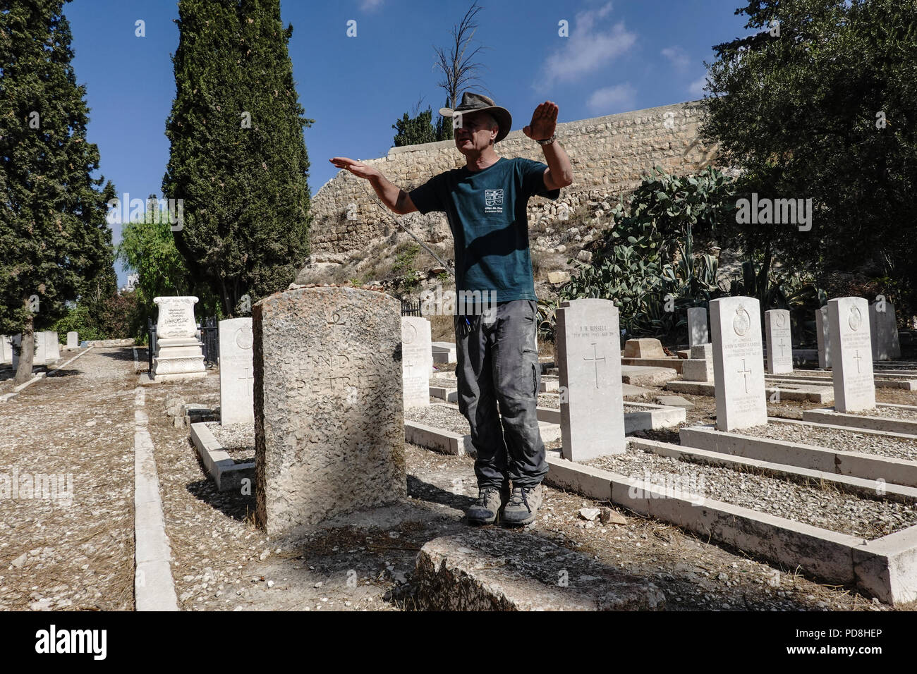 Jerusalem, Israel. 8. August 2018. Prof. Dieter Vieweger, Generaldirektor der Augusta Victoria Campus, Deutsche Evangelische Institut für Archäologie, steht das Grab von Sir William Matthew Flinders Petrie, (1853-1942), ein englischer Pionier der systematische Methodik in Archäologie und Denkmalpflege Artefakte. Unter der Schirmherrschaft von DEI, Deutsche Evangelische Institut für Archäologie, Ausgrabungen auf dem Mt. Zion im Bereich der Anglikanischen Preußischen protestantischen Friedhof einschließlich der so genannten Essener Tor, wobei der Schwerpunkt auf der Innenseite der Stadtmauer und die Abwicklung der alten Jer Stockfoto