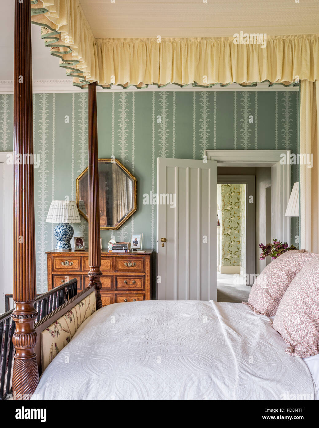Sechseckige vintage Spiegel über Holz Truhe mit vier postered Bed Stockfoto
