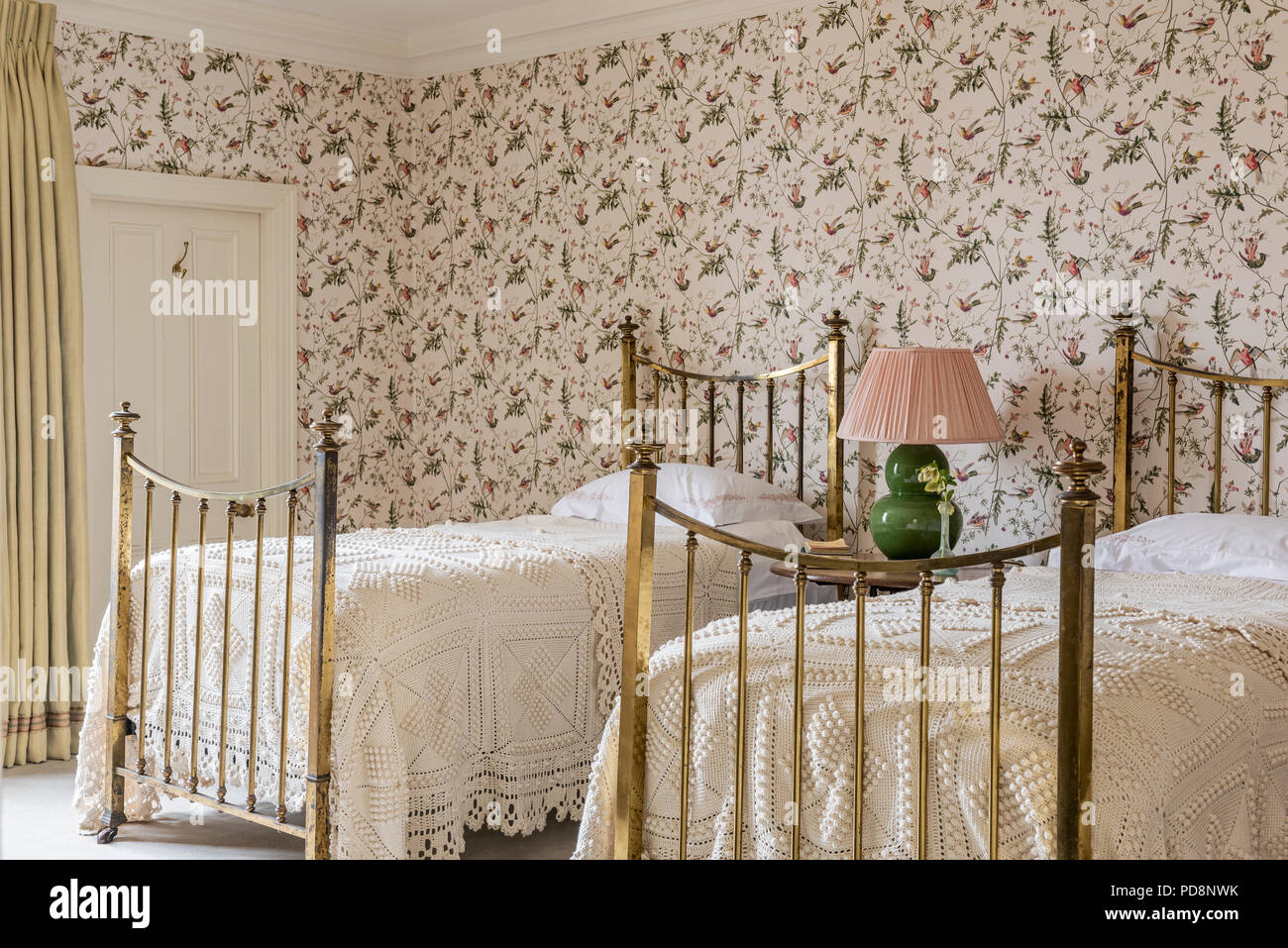 Spitze deckt auf zwei Einzelbetten mit Lampe und Tapeten Stockfoto