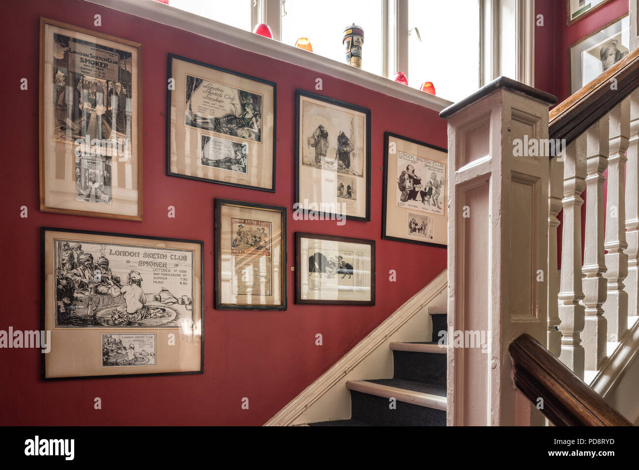 Alte gerahmten Karikaturen auf die rote Treppe Wand des Londoner Sketch Club Stockfoto