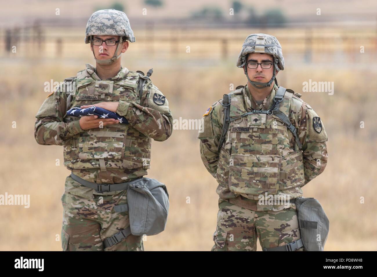 Oklahoma Army National Guard Soldaten, Pfc. Joseph A. Jarmillo und Oscar A. Escorcia, kulinarische Spezialisten mit den 198Th regionale Unterstützung der Konzernzentrale und die Konzernzentrale in Phoenix, stehen bereit, die amerikanische Flagge auf der Feierstunde zum Tag der Unabhängigkeit, 4. Juli 2018, am Fort Hunter Liggett, Calif. Das 198Th RSG HHC ist am Fort Hunter Liggett für einen 21-tägigen Training Mission zur Unterstützung der Bekämpfung der Support Training (CSTX) 91-18-01, eine Übung, die von 91 der Armee finden Abteilung Weiterbildung durchgeführt, 4. Juli 2018 feiern zu erhöhen. (Oklahoma Army National Guard Foto: Staff Sgt Stockfoto