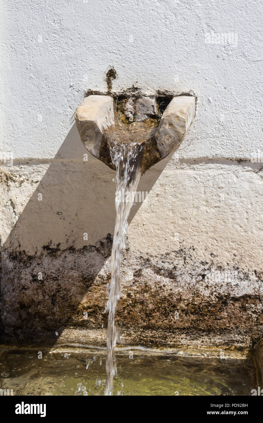 Wand mit einem Wasserhahn und fließendes Wasser. Erfrischung für die Menschen draußen. Estoi, Portugal. Stockfoto