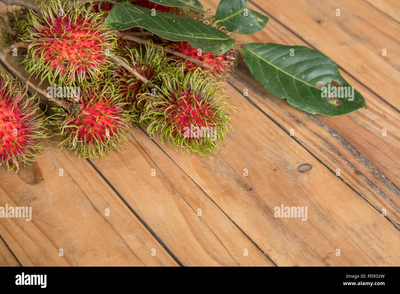 Roten rambutan Nephelium lappaceum auf broun Board. Obst tropischen Baum der Familie Sapindaceae, beheimatet in Südostasien, in vielen Ländern angebaut Stockfoto
