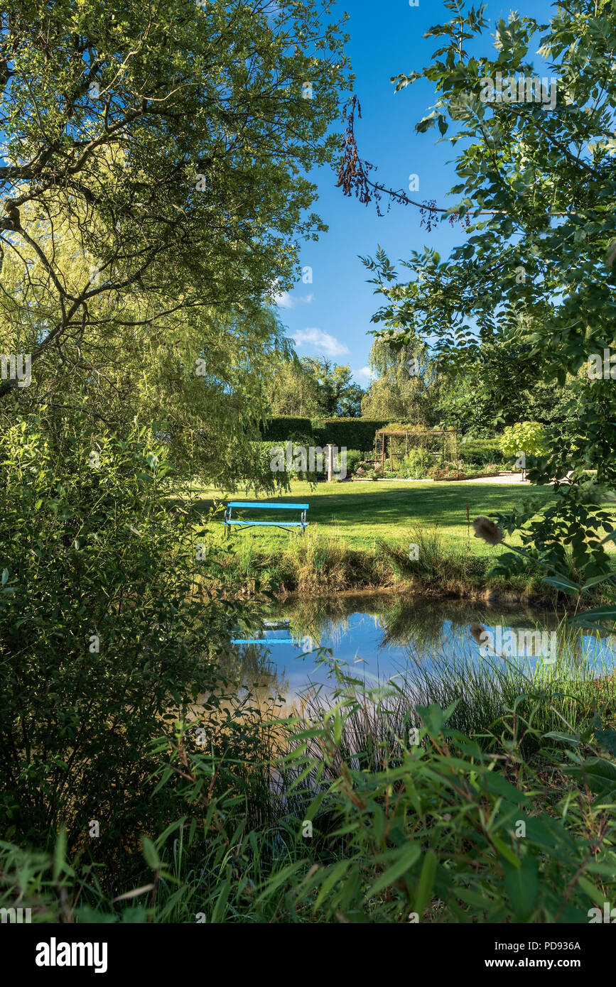Garten Sitzbank mit Blick auf den Teich im malerischen englischen Country Garden Stockfoto