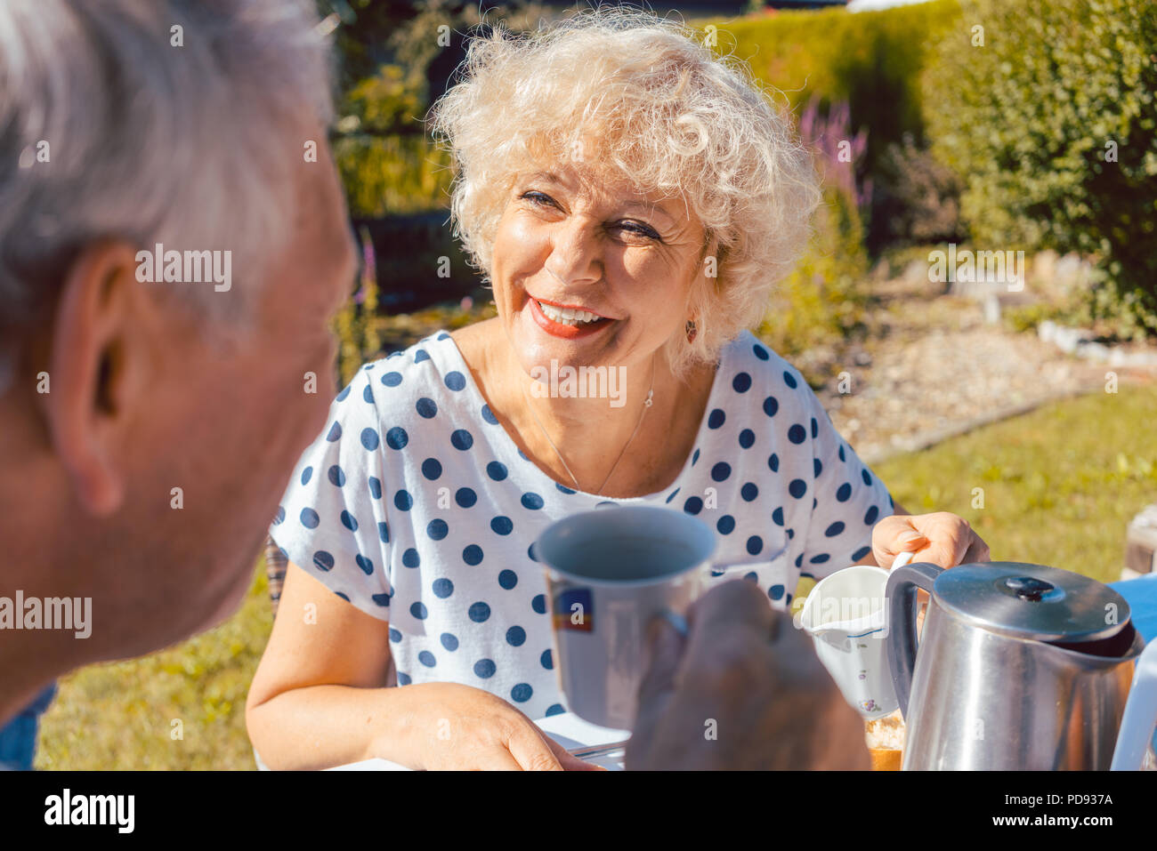 Gerne ältere Paare essen Frühstück in Ihrem Garten im Freien Stockfoto