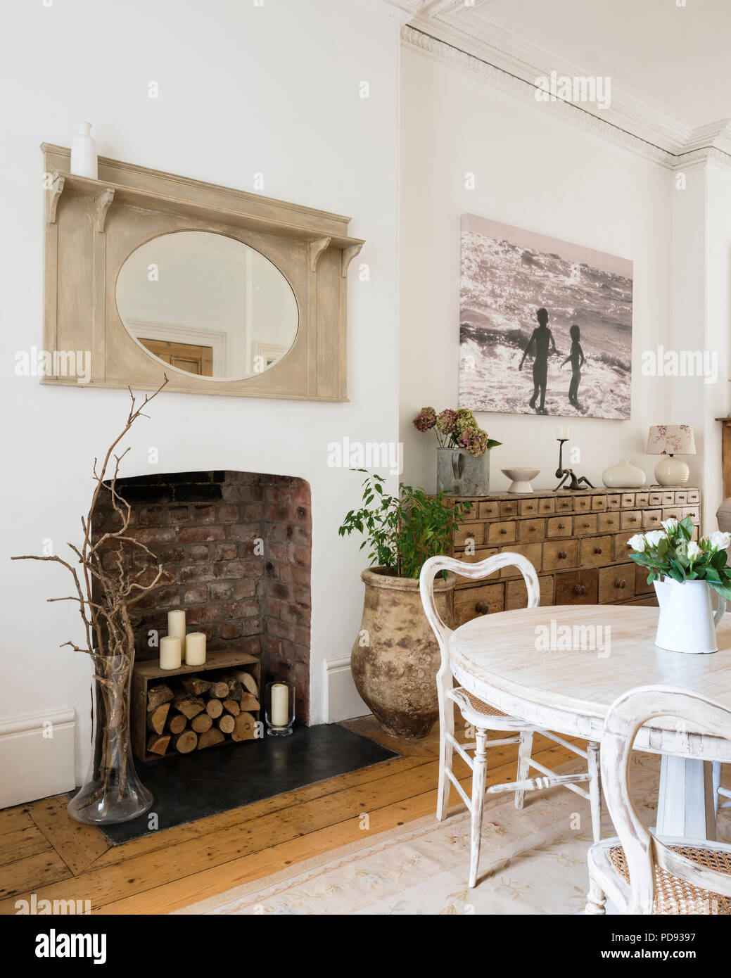 Weißer runder Tisch und Rattan Stühle in hellen und geräumigen Wohnzimmer mit großen apothcary Cabinet Stockfoto