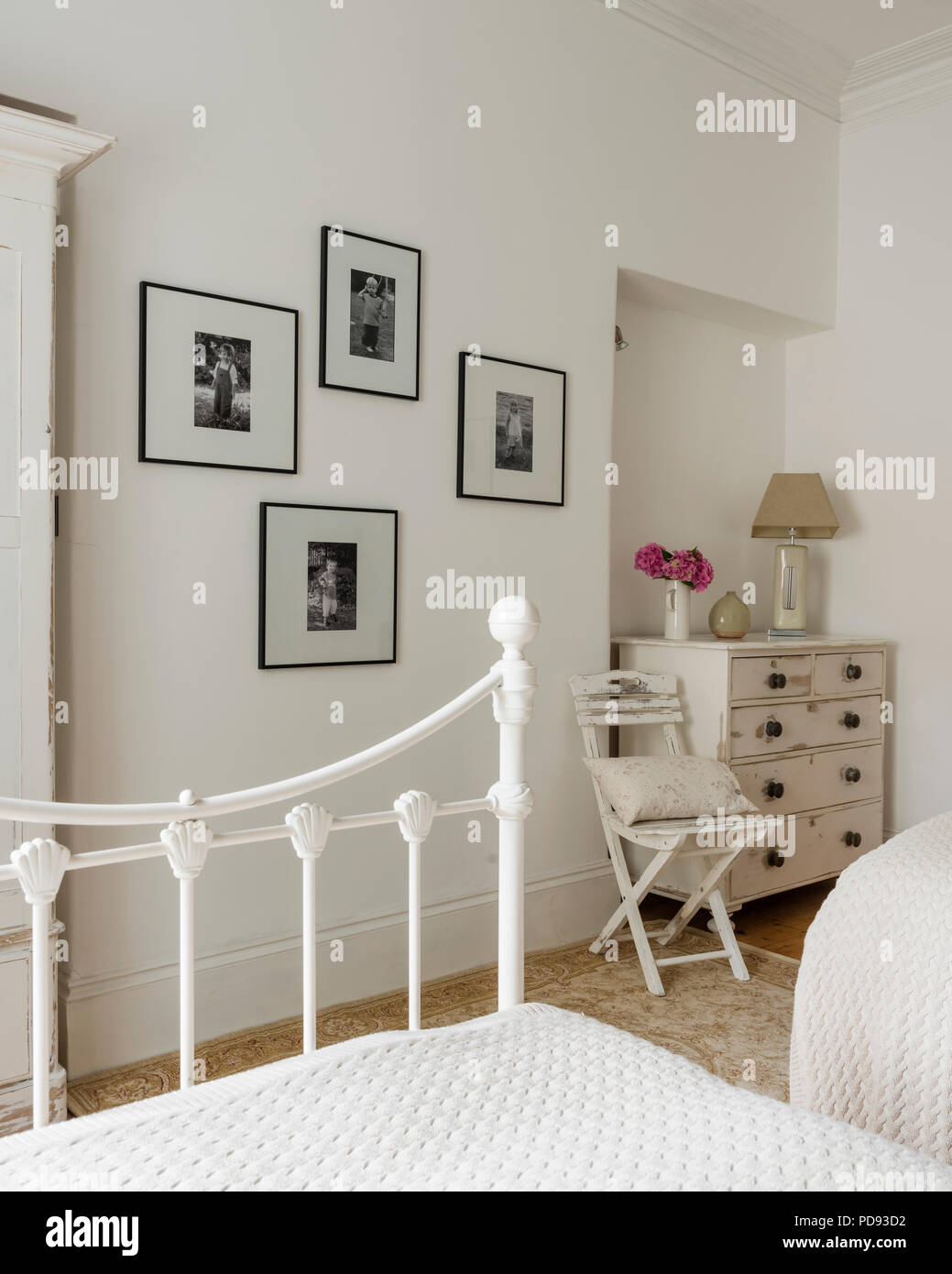 Schwarze und weiße Familie Fotos schmücken die Wand eines Gästeschlafzimmer mit alte Kommode und Patchwork Tagesdecken Stockfoto