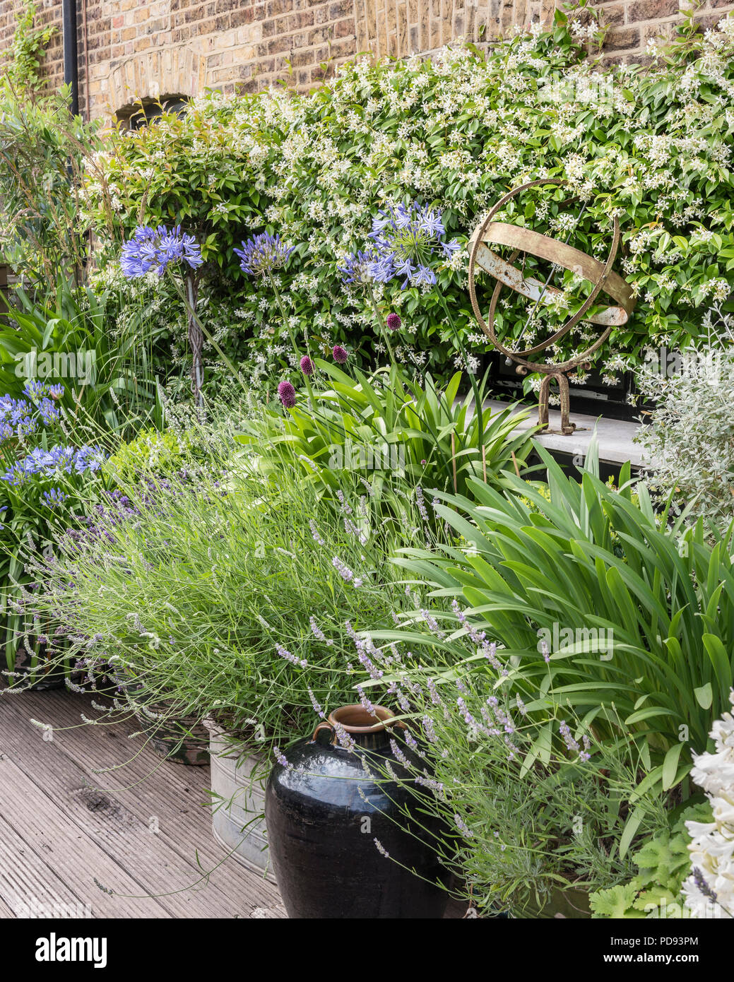 Rostiger Skulptur Garten ledge in unter den Agapanthus, Lavendel und Jasmin Stockfoto