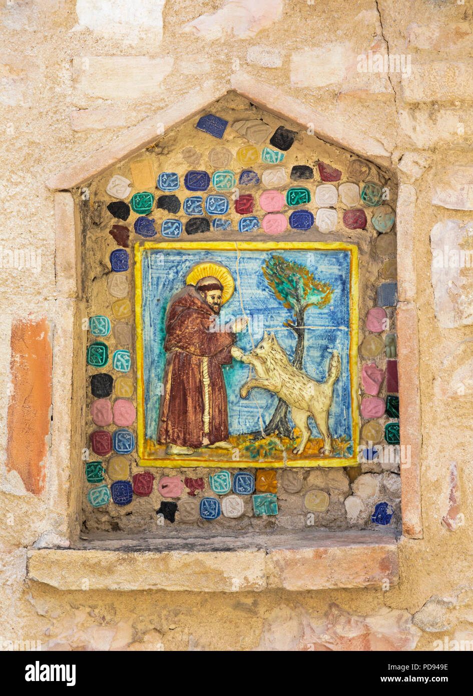 Assisi, Perugia, Umbrien, Italien. Keramische Fliese des Hl. Franziskus von Assisi Segen, einen Hund oder Wolf. Stockfoto