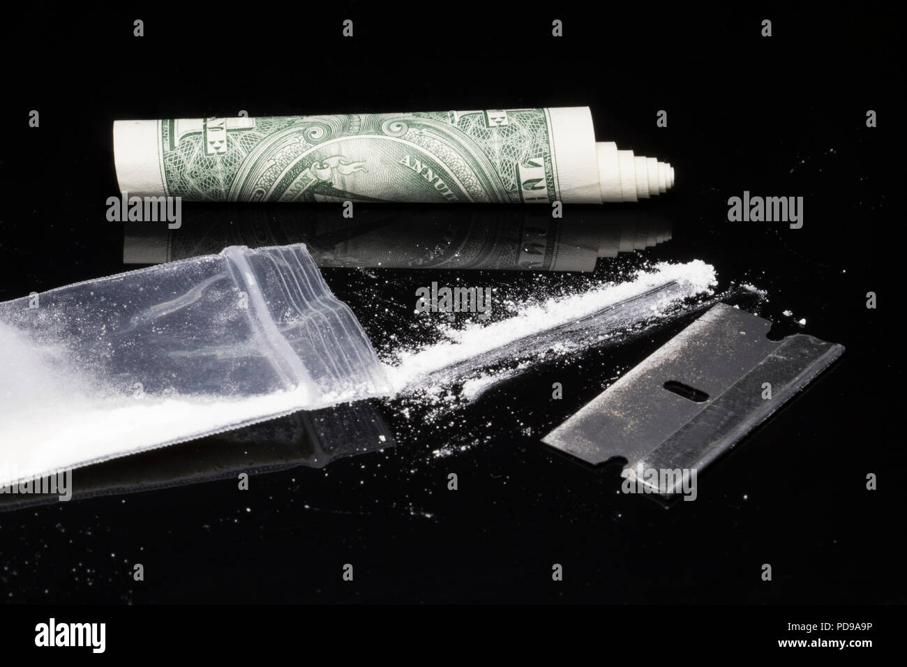 Kokain, Rasierklinge und rollte Dollar Bill. Party Drogen auf den Aufstieg und der Krieg gegen Drogen. Stimulanzien und toxische illegale Drogen. Stockfoto