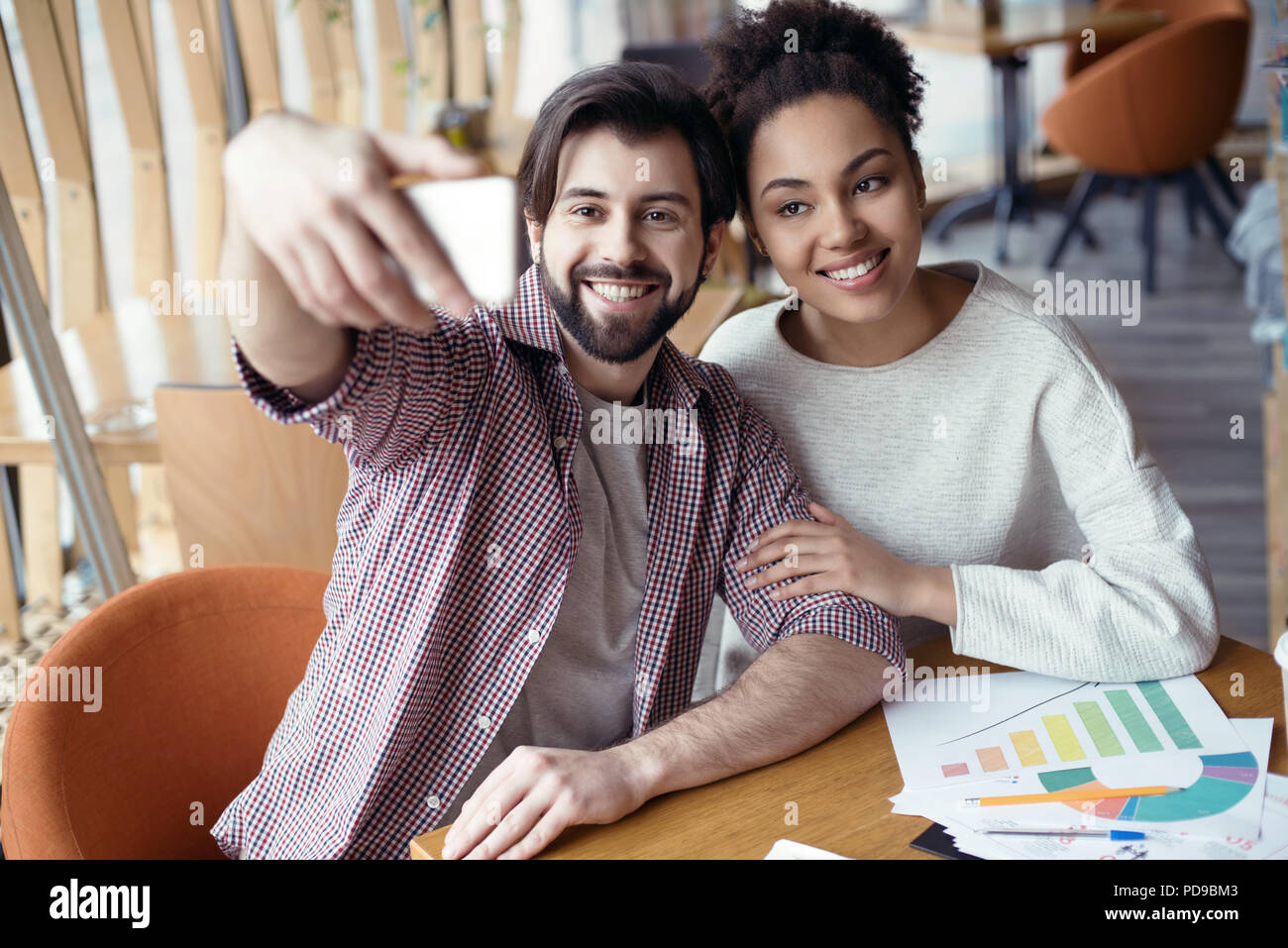 Junge Leute Mann und Frau gemeinsam Coworking an den kreativen stilvolle Büro am Tisch unter selfie Bilder lächelt fröhlich Sitzen Stockfoto