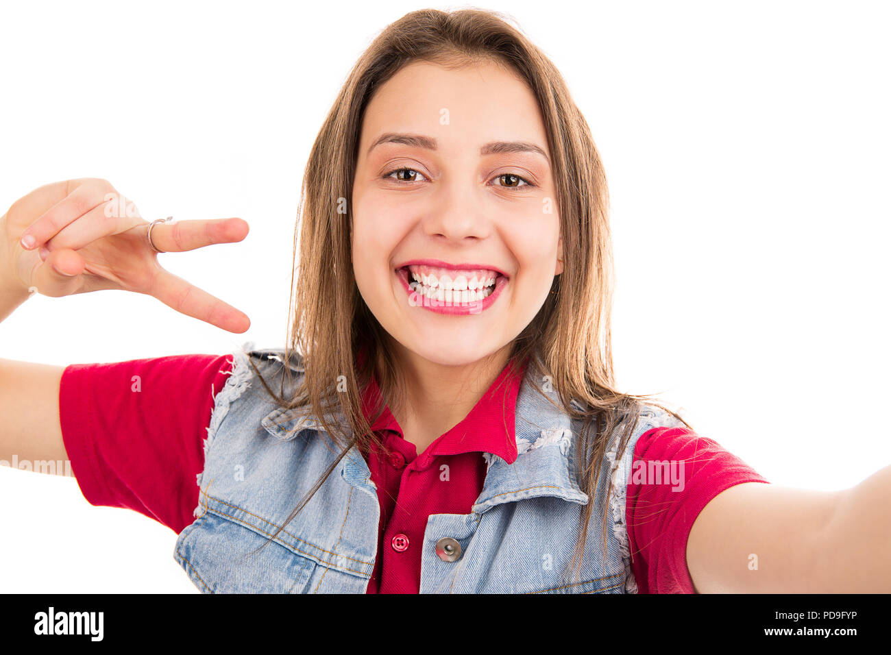 Süße Frau in Jeans Jacke mit zwei Fingern und lächelnd an der Kamera auf weißem Hintergrund unter einem selfie Stockfoto