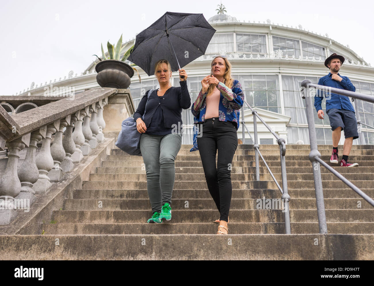 Kopenhagen, Dänemark - 7. Juli 2017. Menschen, die während der Regen auf dem Kopenhagener Botanischen Gärten. Das Palm House, historischen Gewächshaus. Stockfoto
