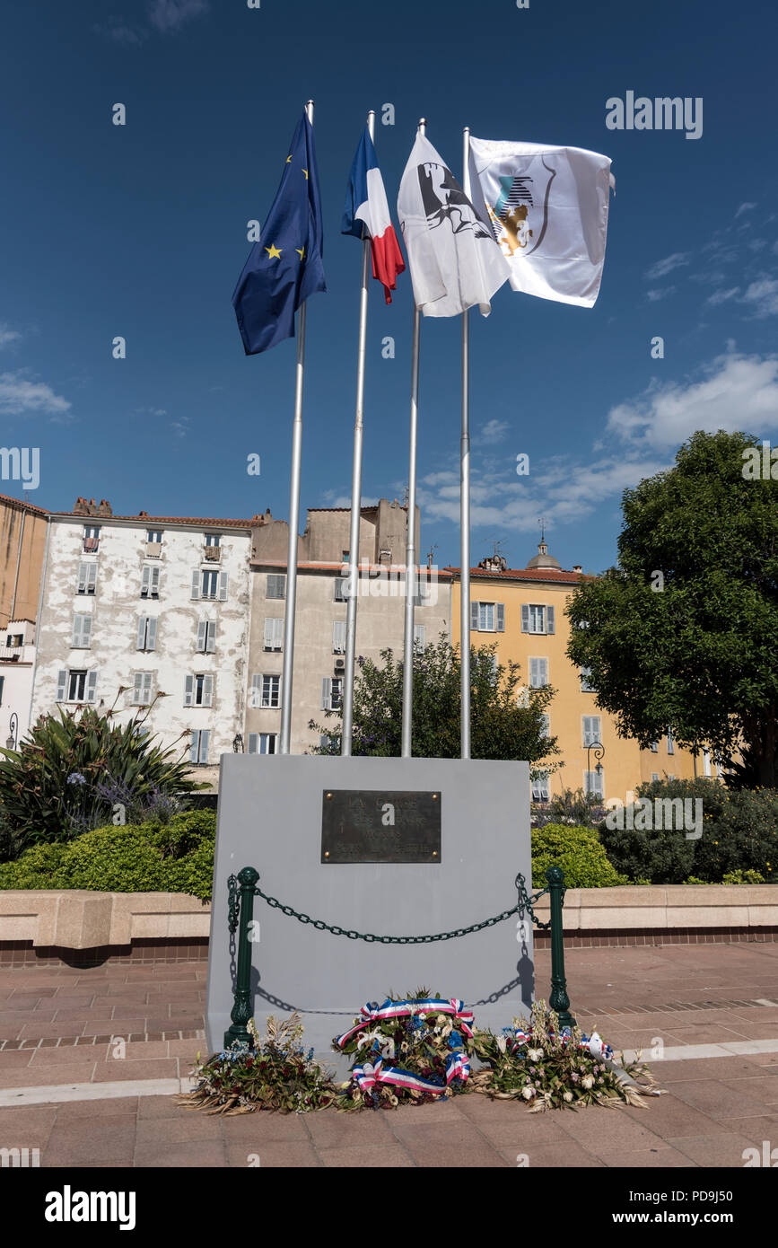 Die EU, Französisch, Korsika und Stadt Flaggen über ein kleines Denkmal oder Memorial: - La Corse ein Ses Enfants Morts Pour La Patrie - Korsika hat ihre toten Kinder Stockfoto