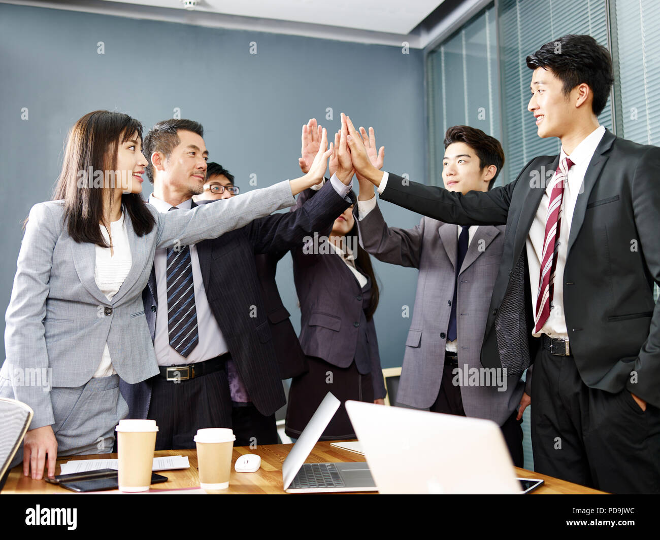 Team von Asian Business Leute, Männer und Frauen die Hände zusammen, Entschlossenheit und Geschlossenheit zu zeigen. Stockfoto