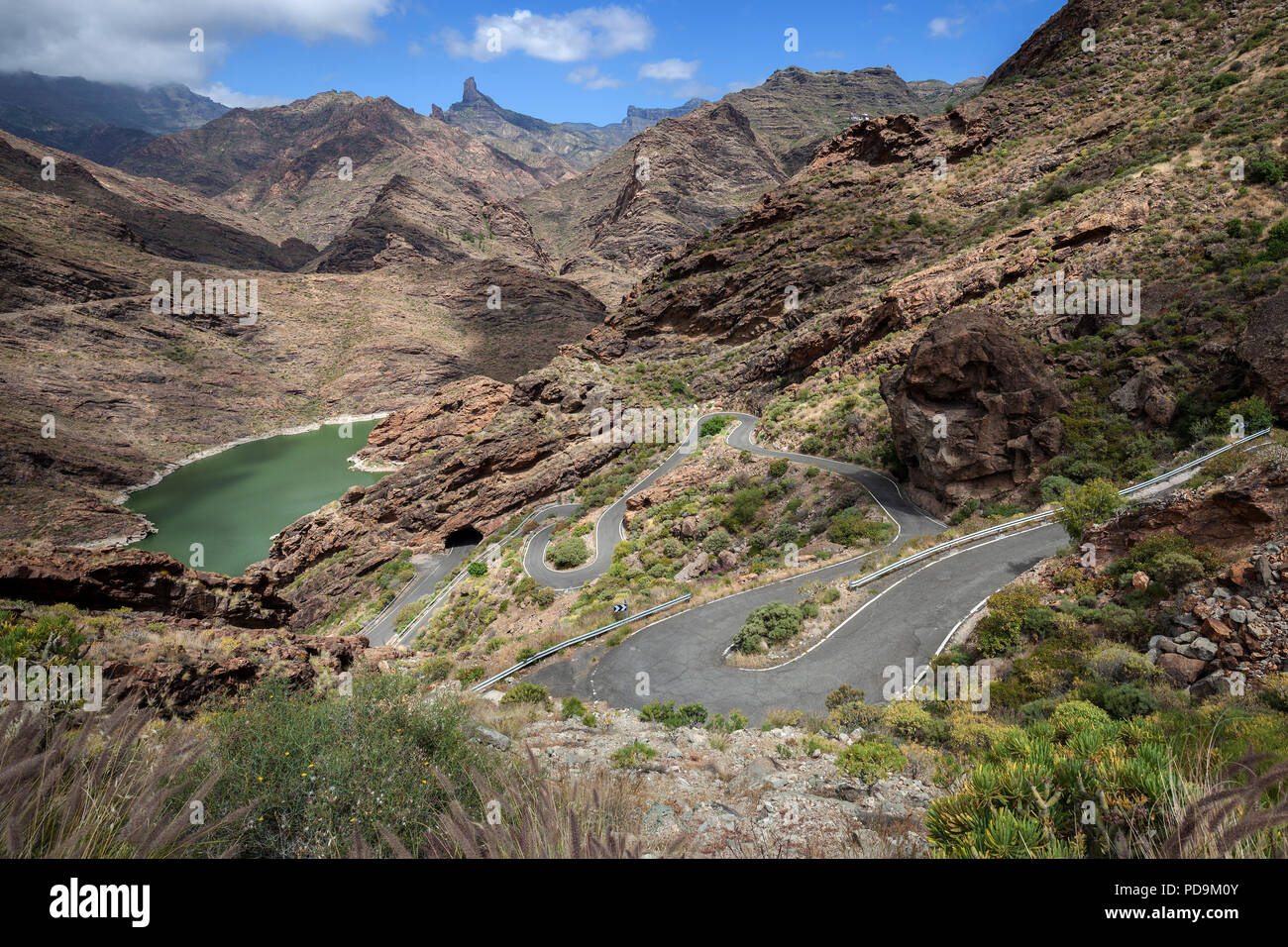 Vulkanische karge Berglandschaft mit Aussicht auf den Stausee Presa del Parralillo, kurvenreiche Straße GC 606, El Carrizal Stockfoto