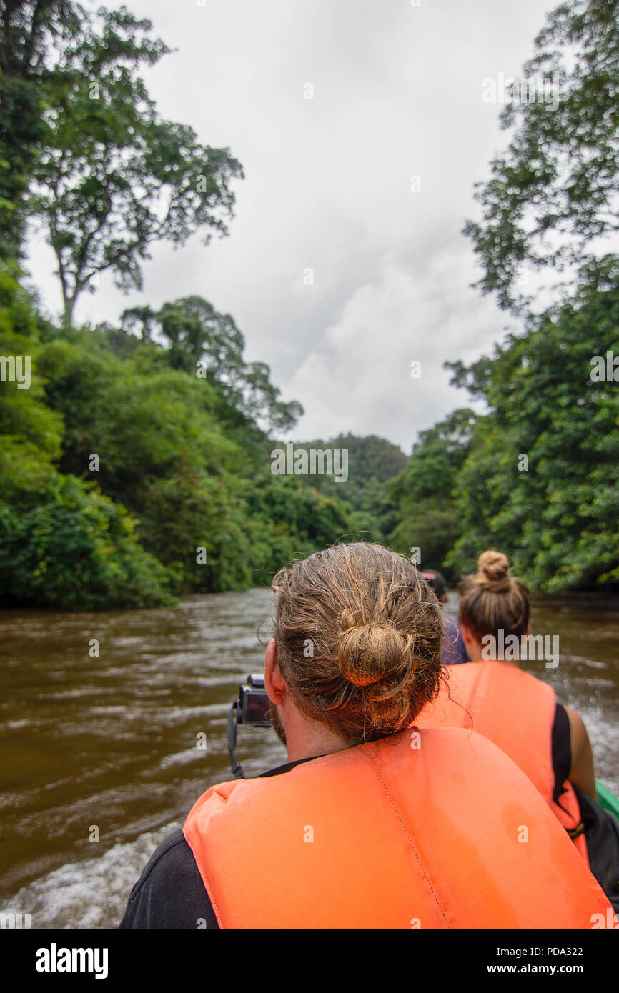 Westliche Touristen in bunten Schwimmwesten nehmen Fotos und ihre Sehenswürdigkeiten Bootsfahrt entlang eines Flusses durch schwere Regen entlang eines Flusses schlucken genießen Stockfoto