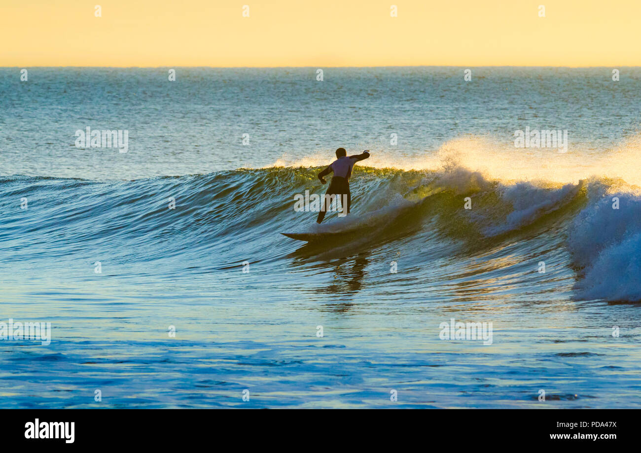 Silhouetted Surfer reiten eine kleine Welle in Bells Beach, Great Ocean Road, Victoria, Australien Stockfoto