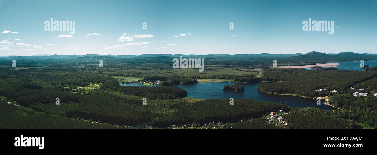 Antenne drone Panoramablick auf das Land der Seen Landschaft, tief Mischwald, Bergen im Hintergrund, lange Panorama im Sommer Abend in Stockfoto