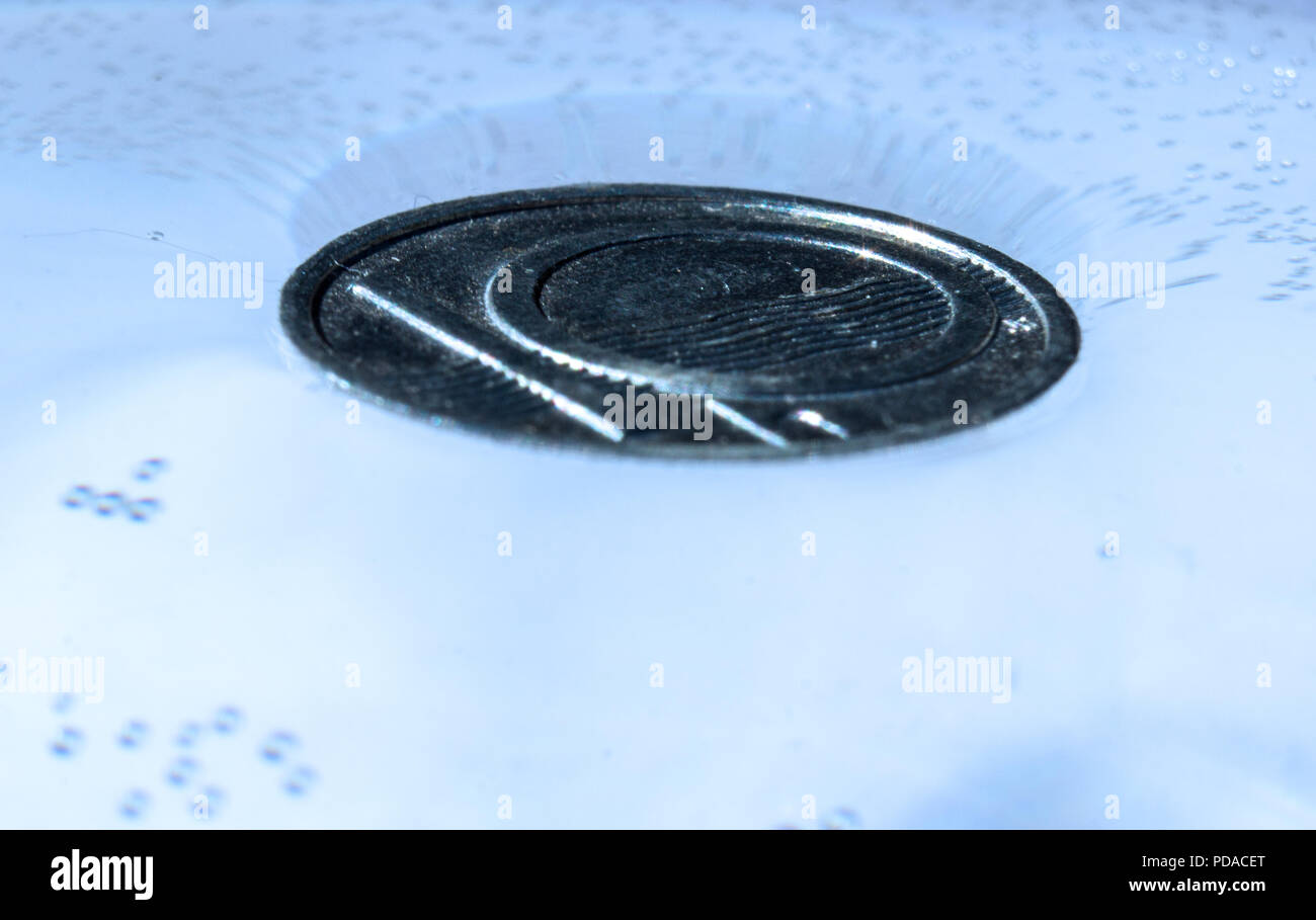 Isolierte Münze in ein Glas Wasser schwimmt auf der Wasseroberfläche - Oberflächenspannung physikalische Gesetze Stockfoto