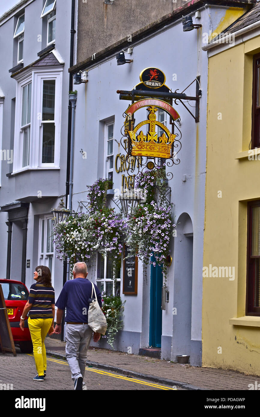 Zwei Urlauber schlendern Sie vorbei an der Crown Inn - ein Gehirn Brauerei Public House im unteren Frog Street, Tenby, Wales Stockfoto