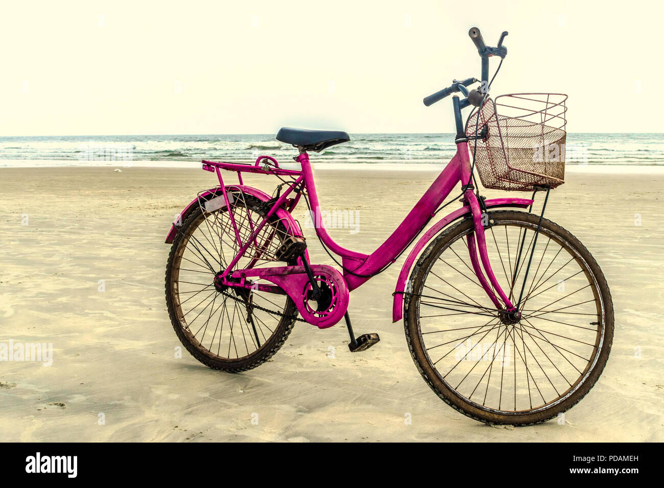 Schöne rosa gefärbten Damen Fahrrad geparkt am Strand auf Sand mit stetigen  Wellen im Meer im Hintergrund und sichtbaren Horizont am Abend isoliert  Stockfotografie - Alamy