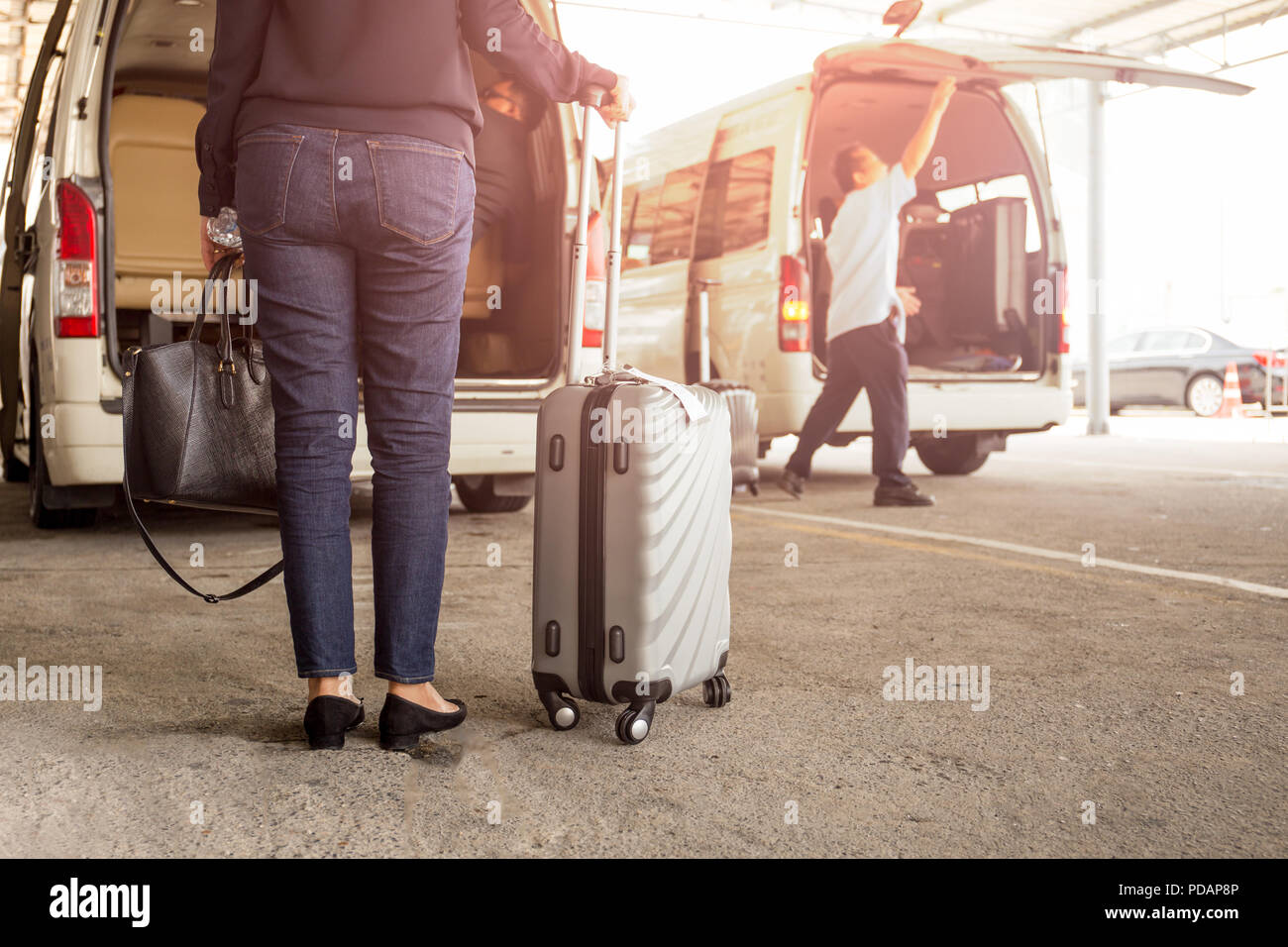 Frau touristische stehend mit Gepäck mit Abholung Van am Flughafen. Stockfoto