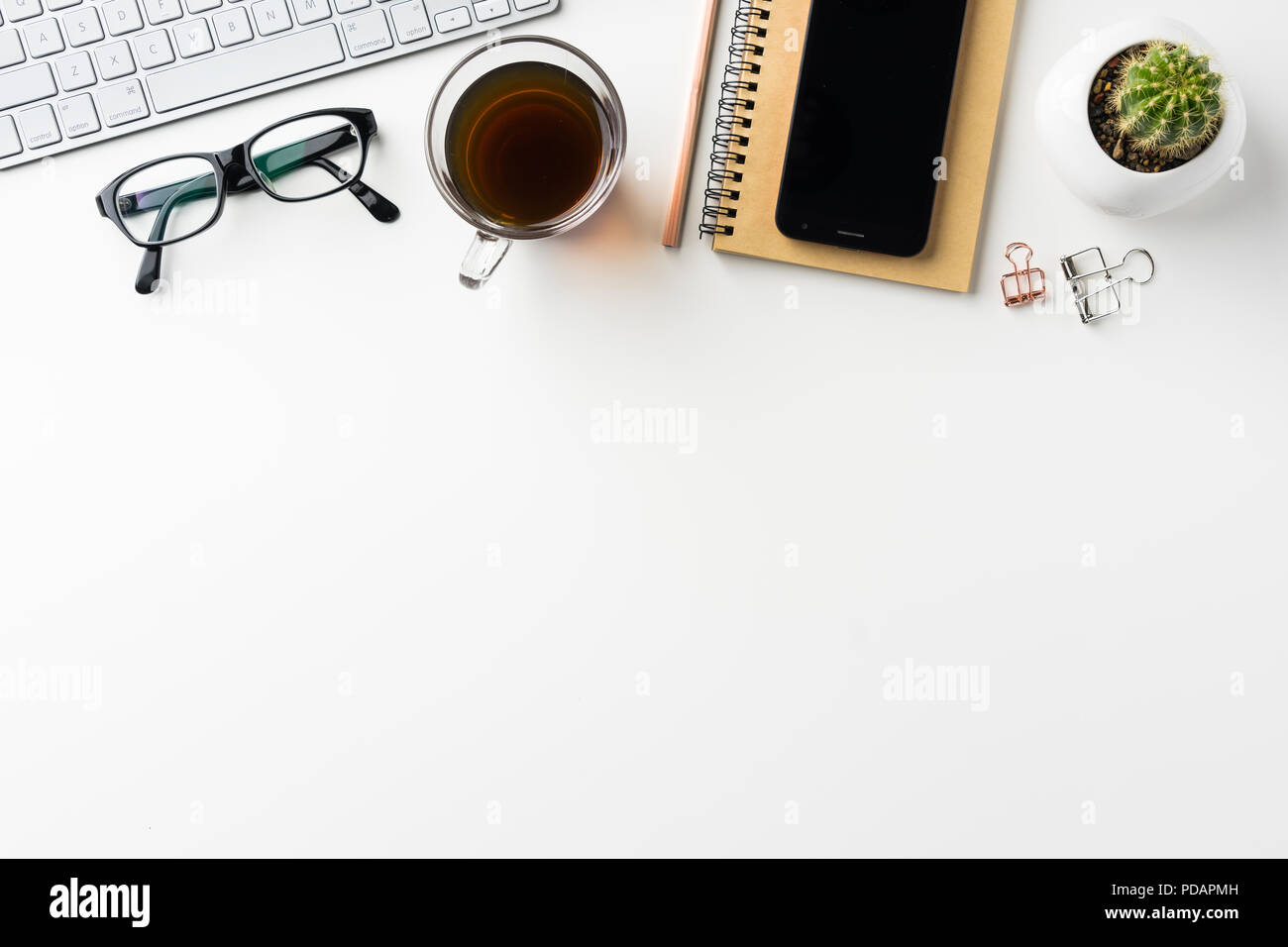 Business-Konzept - Draufsicht des weißen Desktophintergrund mit Notebook, Kaffee, Smartphone, Kakteen und Clip für Modell-design Stockfoto