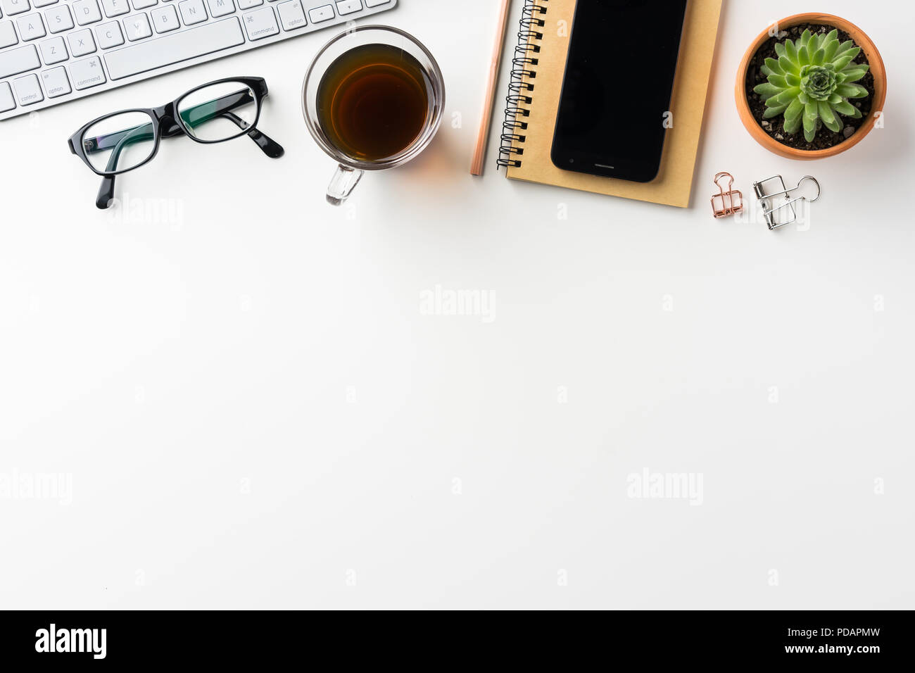 Business-Konzept - Draufsicht des weißen Desktophintergrund mit Notebook, Kaffee, Smartphone, Kakteen und Clip für Modell-design Stockfoto