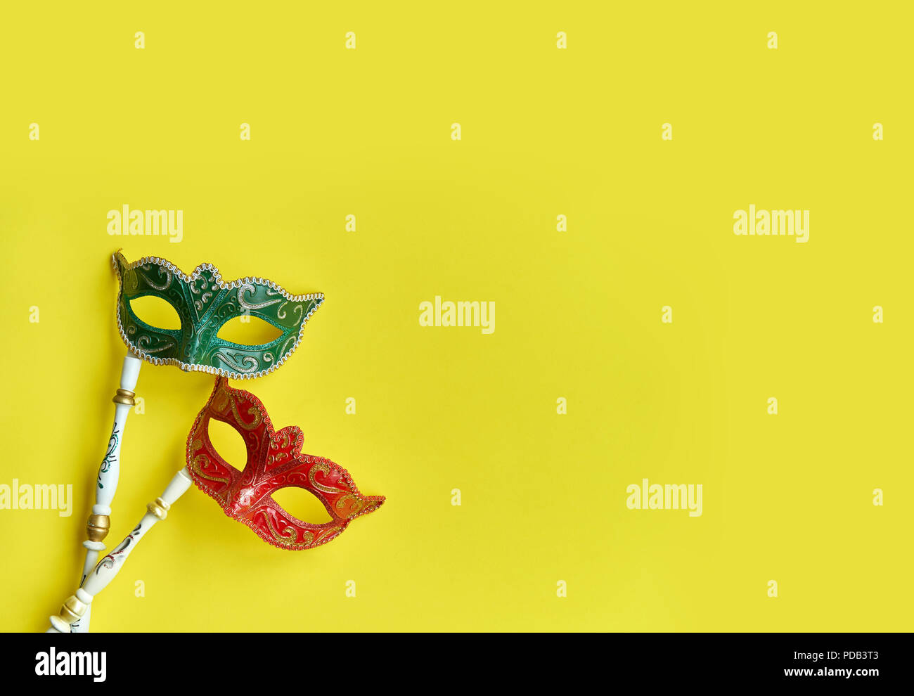 Karneval venezianische Masken in Grün und Rot mit Griff für Photo Booth auf lebendige gelb Hintergrund isoliert, Fancy Maske mit Kopie Raum Stockfoto