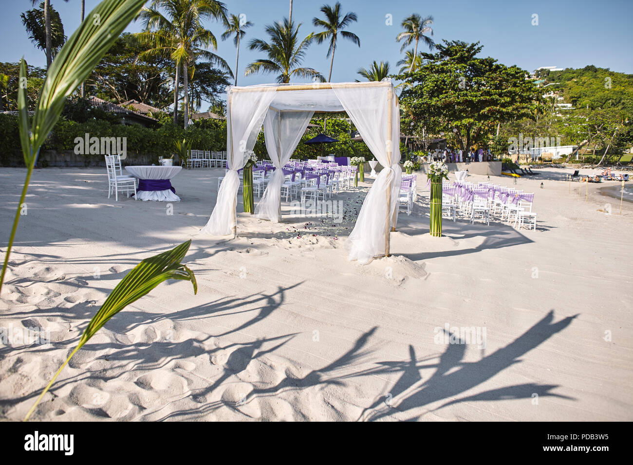 Hochzeit am Strand Veranstaltungsort Einstellungen am Meer auf dem weißen Sand, Bögen und Altar decoratiing mit weißen weichen Stoff auf der Bambus Rahmen weiß Chiavari Cha Stockfoto