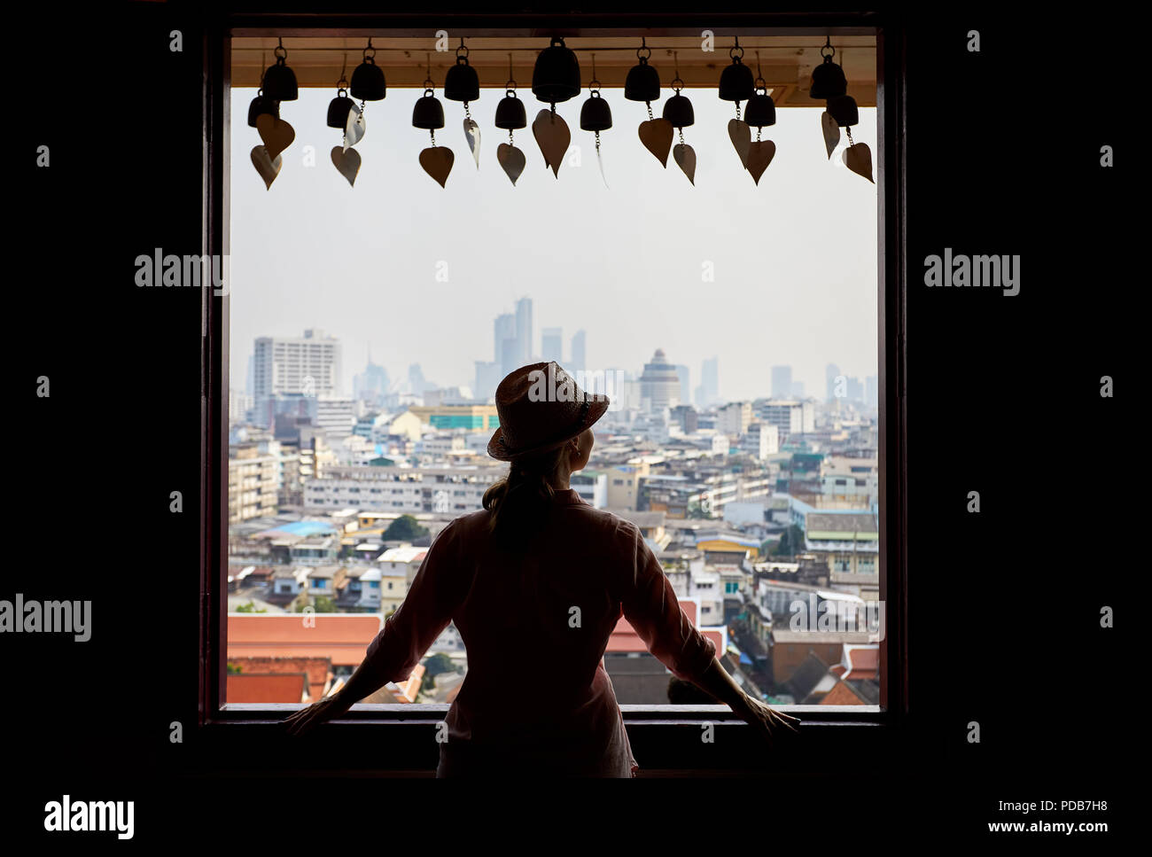 Silhouette der touristischen Frau im Fenster nach Bangkok Blick auf die Stadt der Wolkenkratzer Geschäftsviertel von Goldenen Berg Pagoda Wat Saket an bedeckt Stockfoto