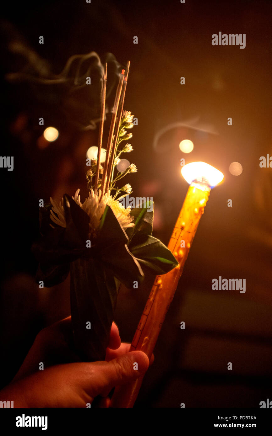 Hand mit traditionellen thailändischen Angebot von Weihrauch, Blumen und Kerzen Stockfoto