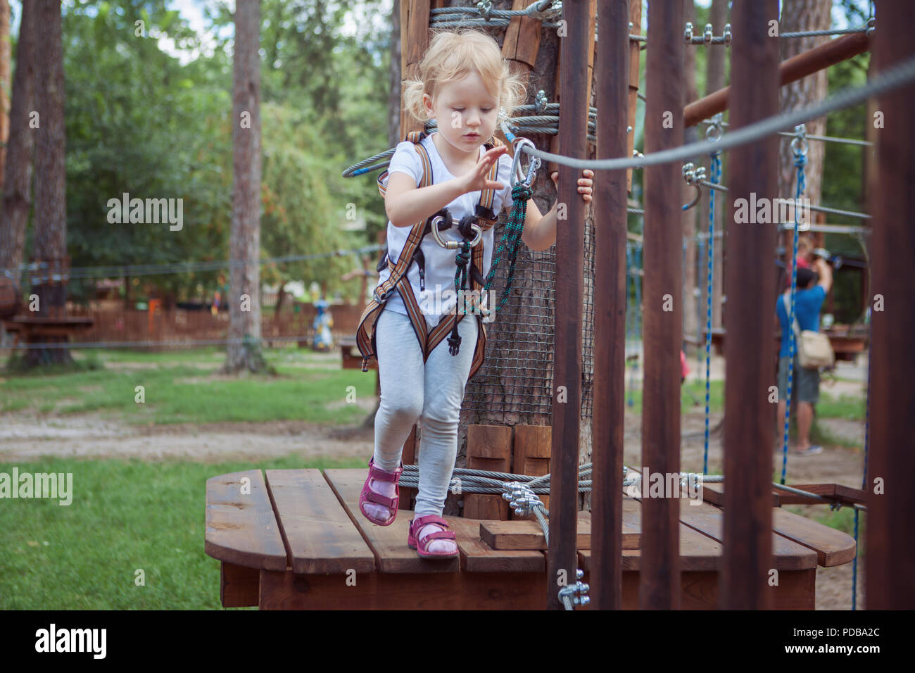 Kleine Mädchen in der Ausrüstung, überwindet das Hindernis in den Seilpark. Stockfoto