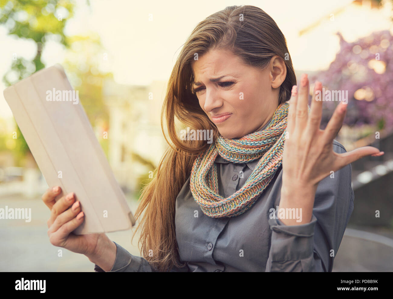 Junge Frau schaut frustriert und mürrisch, unzufrieden mit Tablet-Funktion in schlechte Verbindung auf der Straße Stockfoto